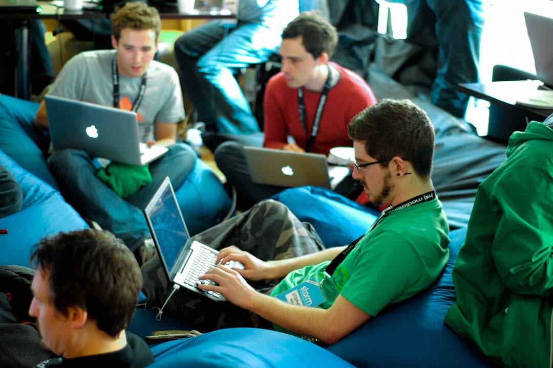 a group of software developers on bean bags working with their laptops