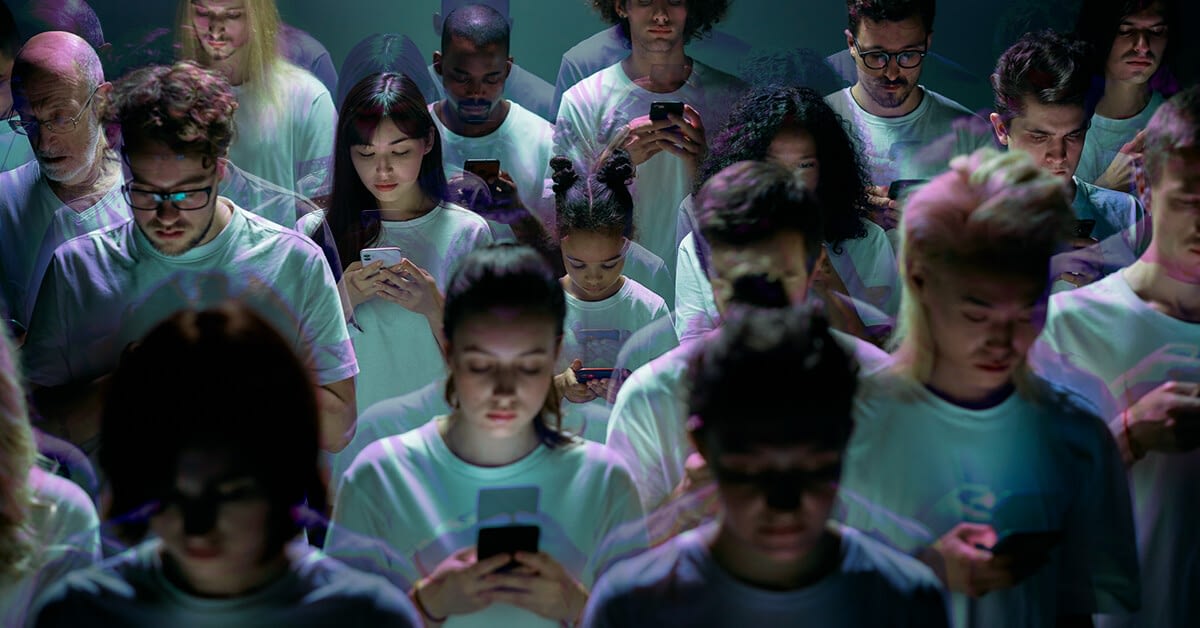 a group of people but each focused on his or her mobile phone, representing a digital divide