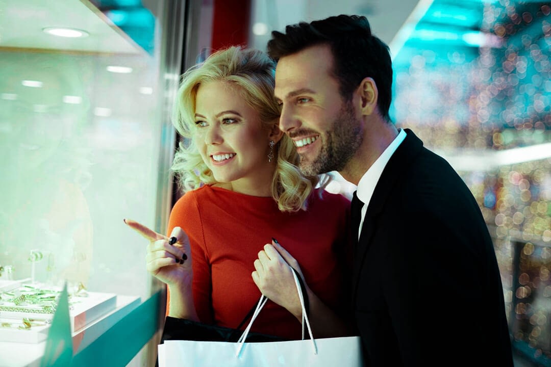 a happy couple closely pointing at a display on a store window