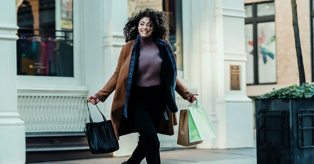 featured image of customer experience, cheerful woman with shopping bags outside a store