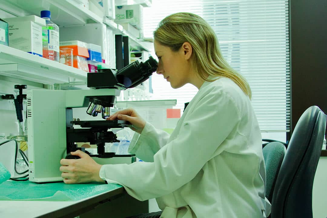 female scientist in a laboratory looking into a microscope