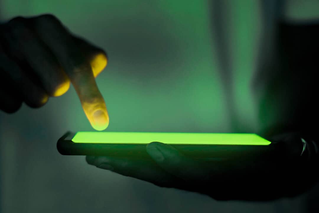 close up view of hands touching glowing screen of mobile phone