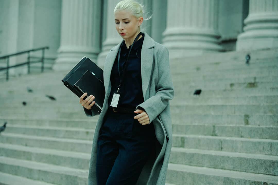 woman on front steps of government building rushing down with documents
