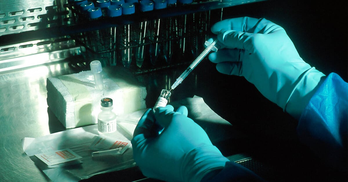 outsourcing clinical trials featured image of close-up view of gloved hands working with laboratory vials